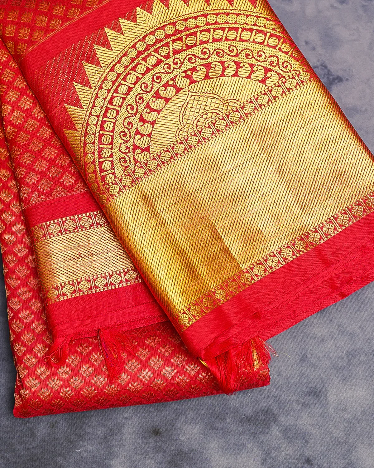 Red silk saree with dense gold jari work across the pallu and woven border