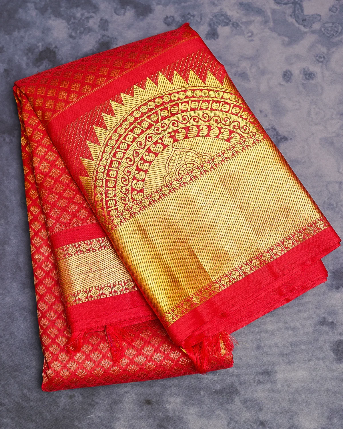Red Kanchipuram silk saree with an ornate gold zari pallu and traditional woven border